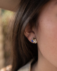 Close-up of an ear wearing a gold earring with a blue gemstone.