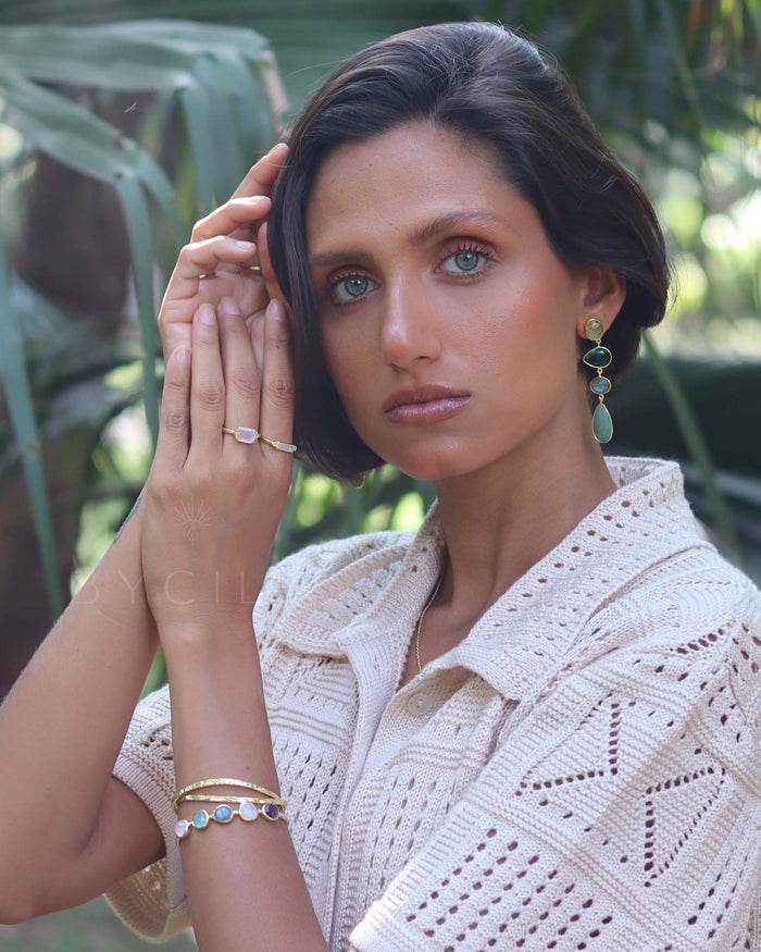 Woman wearing a white crochet top in a natural setting with greenery
